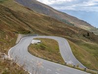 a car drives down a curvy mountain road next to a forest covered hill