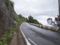 a sign indicating right lane is left behind a steep hill on a street corner next to a steep cliff