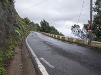 a sign indicating right lane is left behind a steep hill on a street corner next to a steep cliff