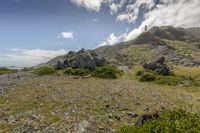 someone flying a kite high up in the air on a mountain with a rocky area