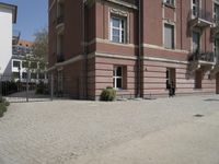 the view from behind the fence looking down at a building, featuring a small man walking across a driveway