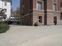 the view from behind the fence looking down at a building, featuring a small man walking across a driveway