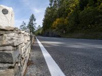 an empty road with several stone blocks on the side of it and trees behind it