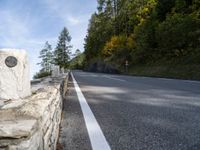 an empty road with several stone blocks on the side of it and trees behind it