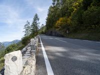 an empty road with several stone blocks on the side of it and trees behind it