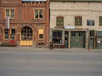 a red fire hydrant sitting in front of an old store window and building next to an open air field