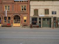 a red fire hydrant sitting in front of an old store window and building next to an open air field