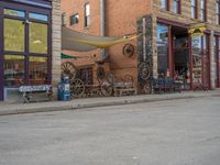 a red fire hydrant sitting in front of an old store window and building next to an open air field