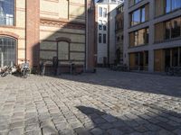 the shadows are made by people walking and riding bikes in the city courtyard of a brick building