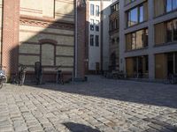 the shadows are made by people walking and riding bikes in the city courtyard of a brick building