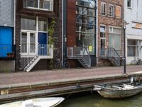 two boats in the water in front of a building with a balcony and a bicycle parked next to it