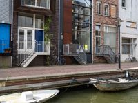 two boats in the water in front of a building with a balcony and a bicycle parked next to it