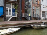 two boats in the water in front of a building with a balcony and a bicycle parked next to it