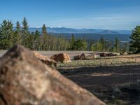 the mountains are visible in the distance from this wide, empty road, overlooking a wide landscape and forest