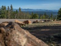 the mountains are visible in the distance from this wide, empty road, overlooking a wide landscape and forest