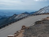 a snow covered road is near a very steep cliff on a clear day the wall is filled with snow and snow