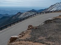 a snow covered road is near a very steep cliff on a clear day the wall is filled with snow and snow