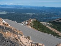 a snow covered road is near a very steep cliff on a clear day the wall is filled with snow and snow