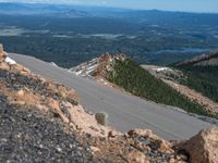 a snow covered road is near a very steep cliff on a clear day the wall is filled with snow and snow