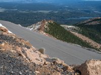 a snow covered road is near a very steep cliff on a clear day the wall is filled with snow and snow