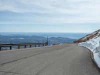 an empty road and a hill overlook the view of mountains and clouds and blue sky