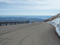 an empty road and a hill overlook the view of mountains and clouds and blue sky