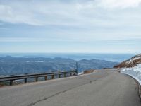 an empty road and a hill overlook the view of mountains and clouds and blue sky