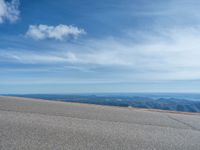 a man is riding his bike down a mountain road with snow and rocks in the background