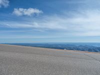 a man is riding his bike down a mountain road with snow and rocks in the background