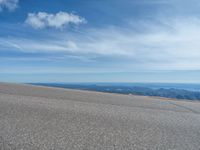 a man is riding his bike down a mountain road with snow and rocks in the background