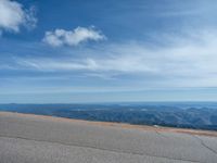 a man is riding his bike down a mountain road with snow and rocks in the background