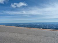 a man is riding his bike down a mountain road with snow and rocks in the background