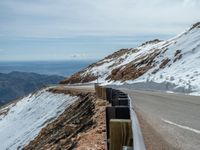 an empty road and a hill overlook the view of mountains and clouds and blue sky