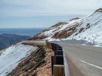 an empty road and a hill overlook the view of mountains and clouds and blue sky