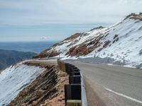 an empty road and a hill overlook the view of mountains and clouds and blue sky