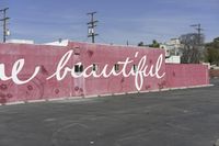 there is a large pink building that says you are beautiful written on it next to a parking lot