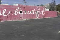 there is a large pink building that says you are beautiful written on it next to a parking lot