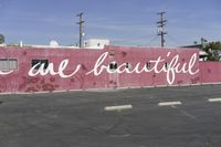 there is a large pink building that says you are beautiful written on it next to a parking lot
