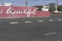 there is a large pink building that says you are beautiful written on it next to a parking lot