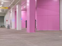 a pink hallway with lots of windows and doors on both sides of it and flooring