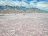 an image of a pink lake in the desert with mountains in the background's horizon