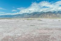 the sand is very pink in this landscape with mountains in the distance and a lot of water in the middle of the land