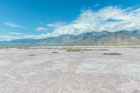 the sand is very pink in this landscape with mountains in the distance and a lot of water in the middle of the land