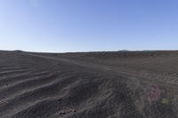 a person on a motor bike riding through the desert on a sunny day with mountains