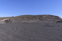 a desert area with some mounds and blue skies in the background with a single motorcycle wheel