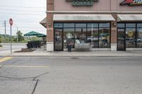 there is a pizza parlor front with a sign in the street for pizza hut store