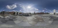 a fisheye lens of the plaza and cityscape with sun peeking through it