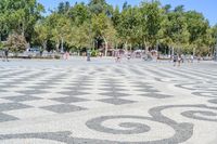 a walkway has black and white patterns on it in a park with trees in the background