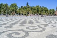 a walkway has black and white patterns on it in a park with trees in the background