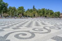 a walkway has black and white patterns on it in a park with trees in the background